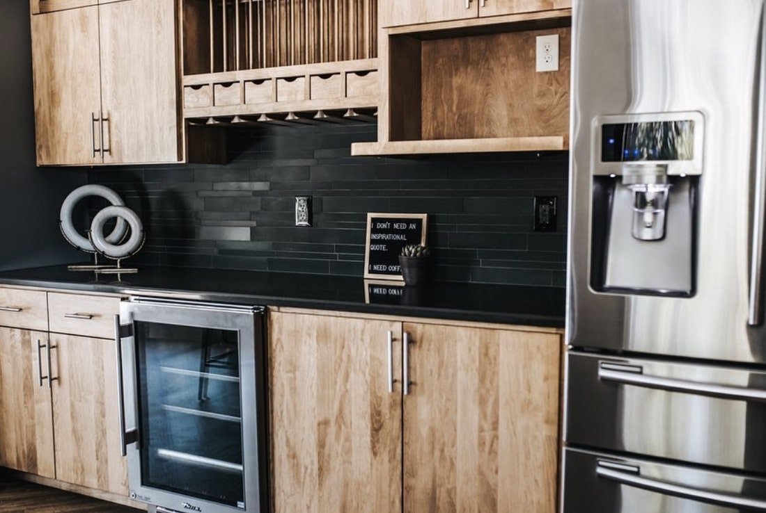 Norstone Ebony Basalt Lynia Interlocking Tile on a Modern Kitchen Backsplash with Black Solid Surface Counter Tops and rustic cabinets